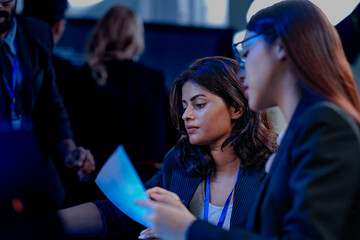 Intense collaboration hub. Diverse AI team deep dive into project data late night. Manager guides Asian colleagues reviewing analytics for a new service launch in tech office.