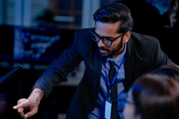Future AI control center. Diverse oversight team monitors autonomous system performance. Analyzing real time execution logs and data streams displayed on advanced computer screens late night.