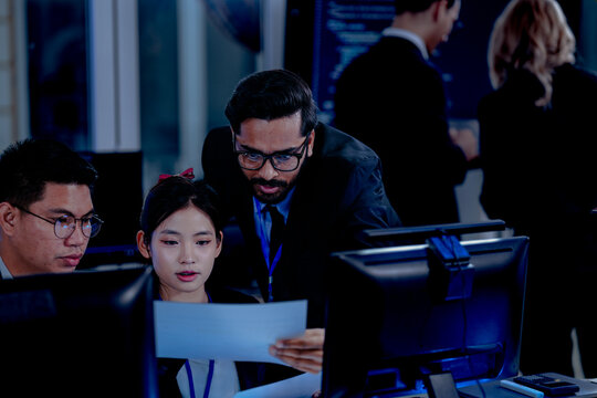 Critical AI model review. Senior data scientist leans over analyzing code output with junior engineers. Debugging complex algorithms together for optimal service performance at night. - Powered by Adobe