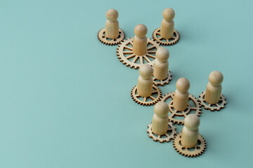 A conceptual image with wooden figures standing on interconnected gears. Teamwork, collaboration, and the interconnected nature of work concept.