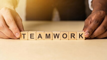 A person holding wooden blocks spelling "TEAMWORK.