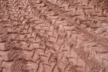 Fototapeta premium Brown mud texture with deep tire tracks and imprint from heavy vehicle wheel creating rough pattern on dirty ground in countryside showing rugged terrain and rural scene