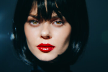 Fototapeta premium Stunning close-up portrait of a woman with dark hair and red lips, showcasing striking emotions and a dramatic aesthetic. Mood-enhancing dark background enhances her beauty.