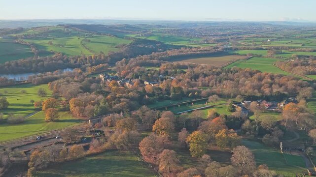 Drone establishing shot of Bretton Hall Manor estate, shows historic Georgian mansion - the manor surrounded by extensive parkland and autumnal woodland, with the Lake nearby orkshire Sculpture Park.
