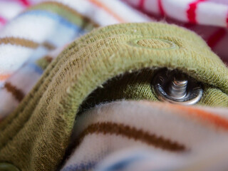 Close up of a circular snap button on a green olive binding with white fabric and line pattern.