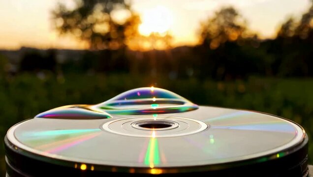 Iridescent Soap Bubble Rests on Reflective CD Surface During Golden Hour Sunset Vibrant Rainbow Colors Reflected Light Physics Phenomenon