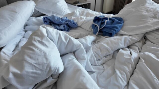 Messy bed with clothes on the sheets in a room
