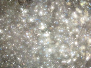 A sea of translucent plastic pellets sparkles under the light, resembling scattered crystals in motion.