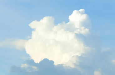 A towering cumulus cloud floats against a serene blue sky, radiating light and depth.