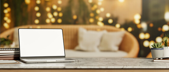White screen laptop and books on marble counter table across woven sofa and string light decorations