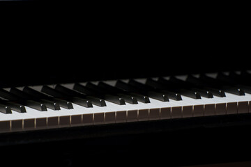 Close-up of piano keys with dramatic lighting and shadow contrast.