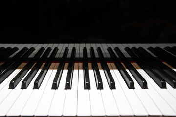 Close-up of piano keys with dramatic lighting and shadow contrast.