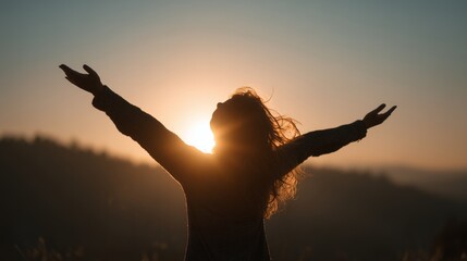 Woman silhouetted against a golden sunset with arms outstretched embracing freedom and joy