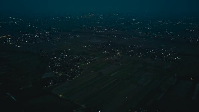 Aerial drone view of a landscape at dusk with fields and buildings