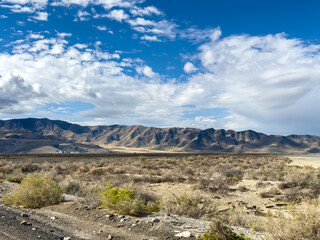 Off road trail with mountain background, blue sky and clouds