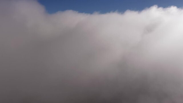 Sunny day reveal from inside the fog clouds on a river valley