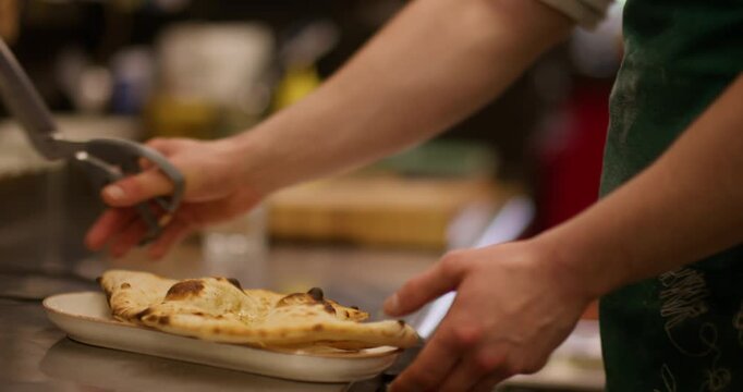 Cutting crunchy pita. Kitchen scissors. Baker serving crispy hot flatbread crust by pieces. Professional restaurant metal utensils.