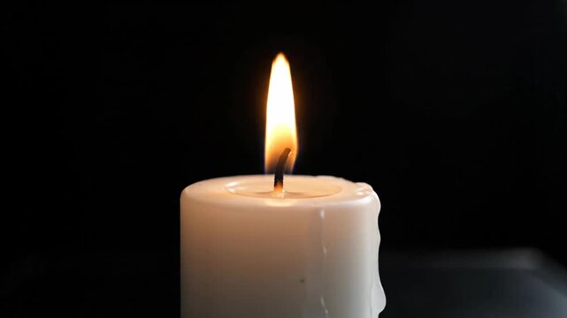 Close up of lit candle flame against black backdrop