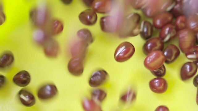 Asian red Azuki mung beans falling into yellow bowl slow motion