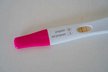 Hand holding pregnancy test showing positive result indoors