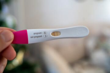Hand holding pregnancy test showing positive result indoors