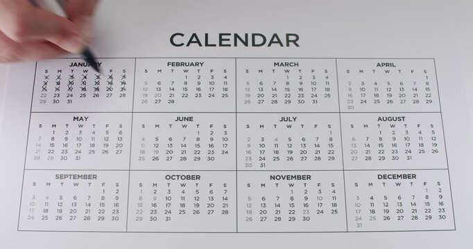 Person marking off days of the month on a white calendar with a black marker, possibly counting down to an important date or event. Marking Dates On Calendar