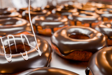 トレイに並んだドーナツに白い液体クリームを垂らす
