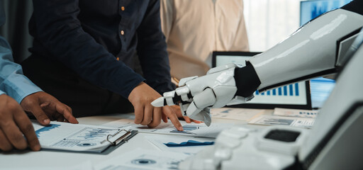 A dynamic meeting scene showcasing human and robot collaboration, highlighting business charts and data, symbolizing the future of teamwork in modern workplaces.Noogenesis