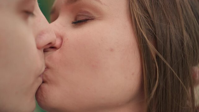 outdoor lovers exchange warm affection, two people share intimate kiss in bright sunlight outside, romantic partners display affectionate gestures amid sunlit scenery and natural surroundings