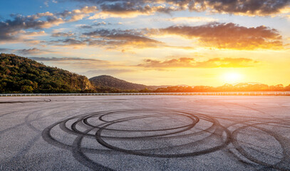 Asphalt race track road and mountain with dramatic sky clouds at sunset