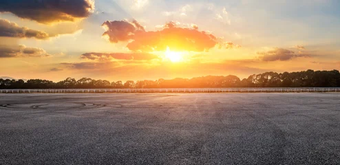 Fotobehang Slaapkamer Empty asphalt race track and green forest with beautiful sky clouds landscape at dramatic golden sunset  © ABCDstock