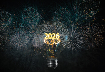 Obraz premium The bulb's filament also says 2026 - Light bulb isolated on black background with fireworks
