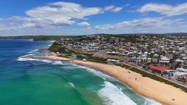 Drone tracking left of Merewether Beach with turquoise water and residential coastline, Australia