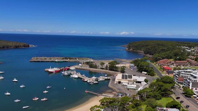Wide aerial backside of Ulladulla coastal town with harbour and surrounding headlands, out to ocean