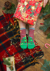 Christmas cozy flat lay with colorful wool blanket fairy lights and winter socks on wooden floor showing warm holiday home atmosphere