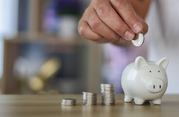 hand is putting a coin into a piggy bank with stack coin 