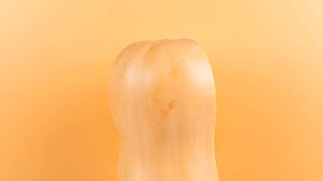 A close-up shot of a halved, vibrant orange squash against a solid, similarly toned background
