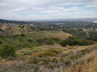 Fototapeta premium Rolling hills with distant city skyline under cloudy sky