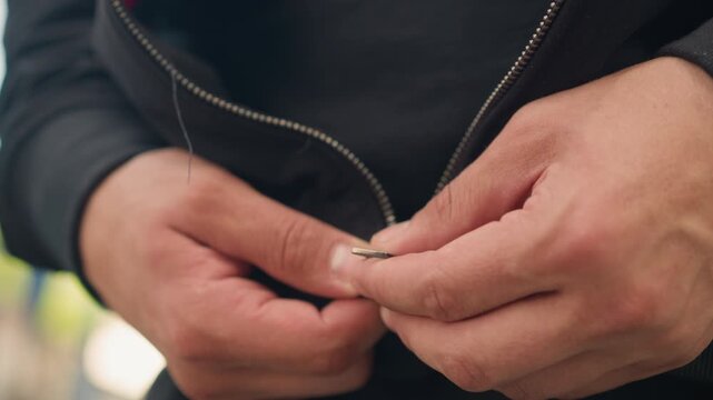 close view of man zipping hoodie before running, caucasian male adjusting hoodie zipper for outdoor morning jog, detailed shot of hands zipping up casual hoodie before morning run outdoors