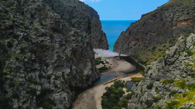 Aerial dolly in Sa Calobra canyon opening toward the sea between towering cliffs, Mallorca Spain