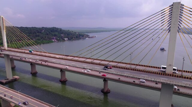 Vehicles moving on Atal Setu bridge with mandovi river and trees at goa. day time, push in shot, drone shot, 4k.