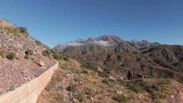 Drone reveal shot of&nbsp;engineered structure of the modern RN Ruta 40 into focus, showcasing extensive concrete retaining wall built into challenging slopes of Cuesta de Miranda, La Rioja, Argentina