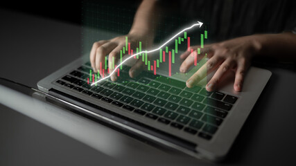 A focused view of hands typing on a laptop keyboard with an overlay of stock market graph and data visualization, representing modern financial trading and analysis. Impute