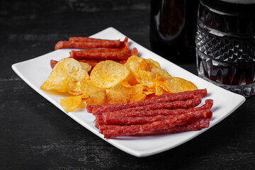 Beer and snack, chips and kabanos on a dark background.