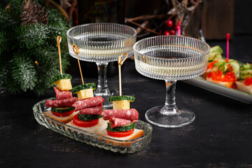 Canapes with salami, cheese, tomato. Christmas and New Year's dishes. Snacks and wine drinks for the holiday table.