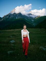 Naklejka premium Mountains, meadow, woman, outdoor fashion travel landscape nature adventure scenery in alpine valley with clouds and grass under a clear sky, stylish casual look and wild landscape mix