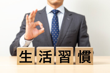 「生活習慣」と書かれたブロックとOKポーズをするビジネスマン