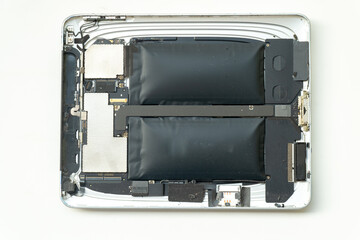 Detailed view of the internal components of a tablet featuring two severely swollen lithium-ion battery cells. The device's metal chassis and circuit boards are visible.