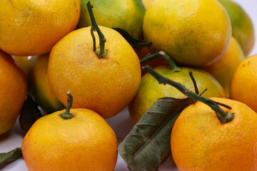 Macro Shot Of A Pile Of Fresh Mandarins, Some With Leaves Still Attached. The Image Emphasizes The Freshness And Organic Origin Of The Citrus Fruit.