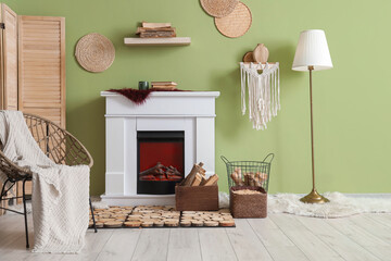 Fototapeta premium Interior of living room with armchair, folding screen, lamp and firewood near fireplace